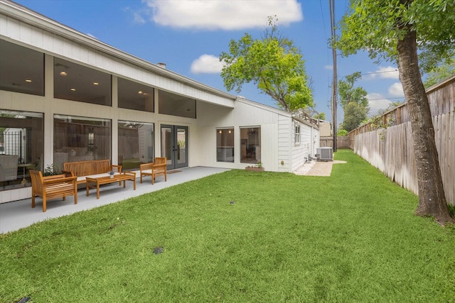 rear view of house with cooling unit, outdoor lounge area, a lawn, french doors, and a fenced backyard