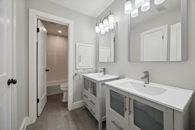 bathroom with two vanities, visible vents, baseboards, and a sink