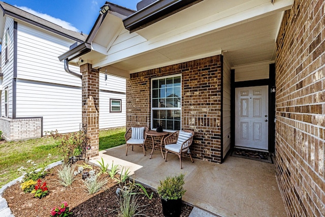 view of exterior entry featuring brick siding and a porch