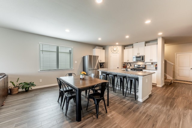 dining space with baseboards, wood finished floors, and recessed lighting