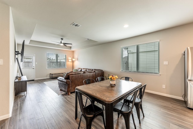 dining room with ceiling fan, baseboards, and a raised ceiling