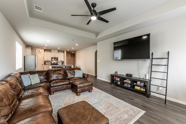 living area featuring wood finished floors, visible vents, a ceiling fan, and baseboards