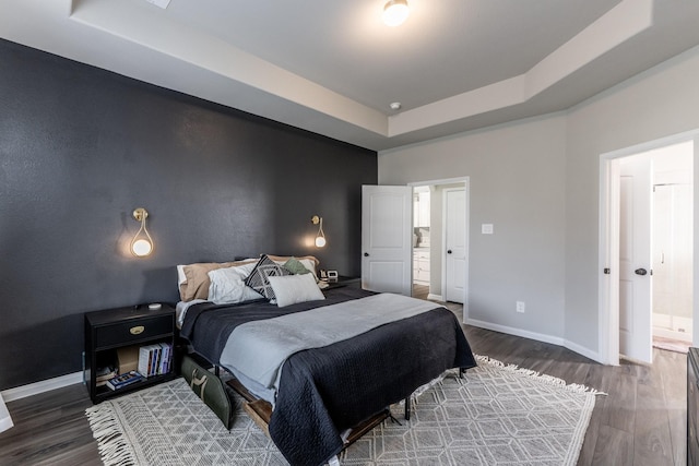 bedroom featuring a raised ceiling, wood finished floors, and baseboards