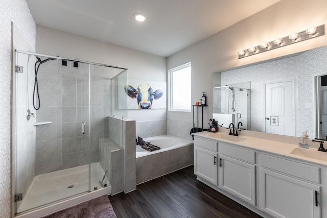 full bath with a bath, wood finished floors, a sink, and a stall shower