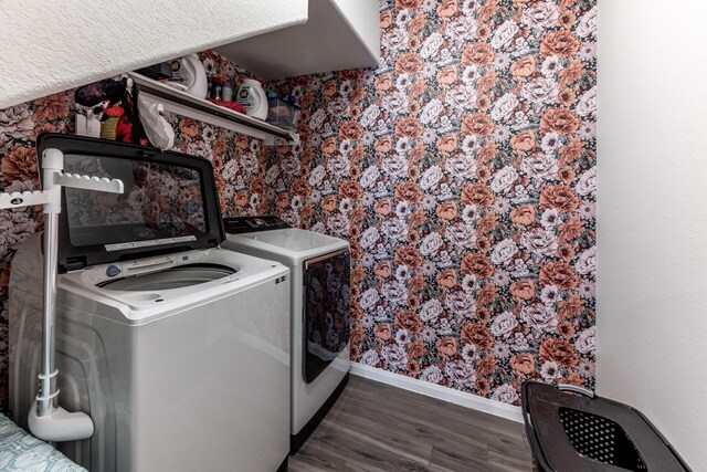 clothes washing area with laundry area, baseboards, wallpapered walls, washer and dryer, and dark wood-type flooring