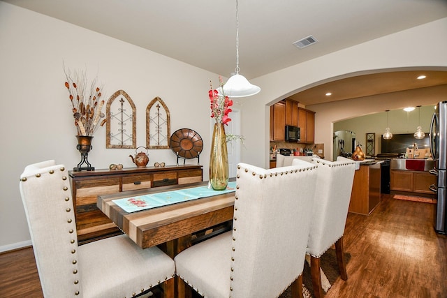 dining room with arched walkways, visible vents, dark wood-style floors, and recessed lighting