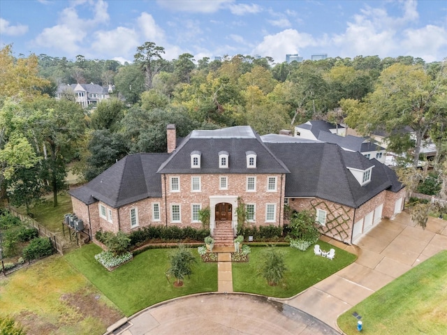 view of front of property featuring concrete driveway, a chimney, a front yard, and a garage