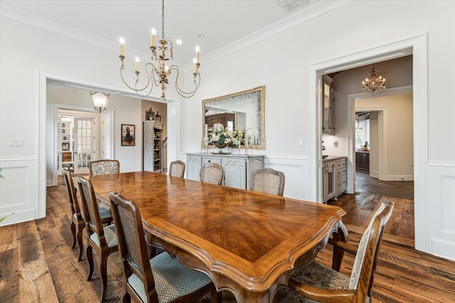 dining room featuring a chandelier, dark wood-type flooring, ornamental molding, a decorative wall, and wainscoting