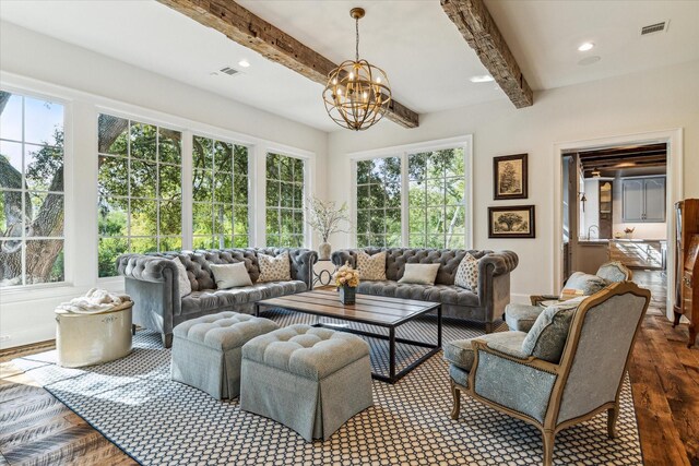 living area with wood finished floors, beam ceiling, plenty of natural light, a chandelier, and baseboards