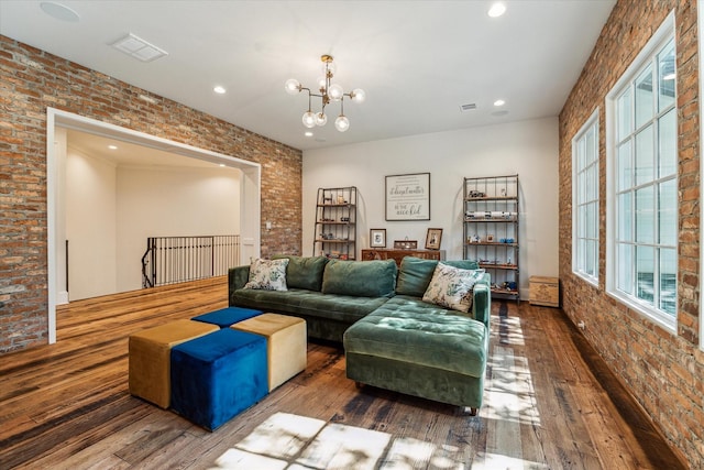 living room featuring brick wall, wood-type flooring, a chandelier, plenty of natural light, and recessed lighting