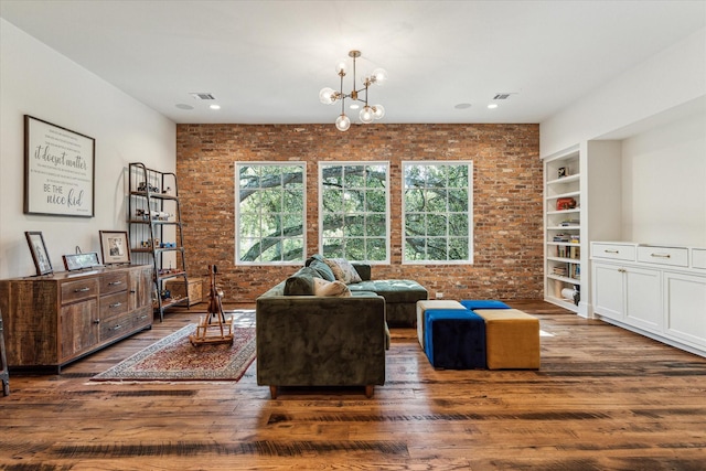 living area featuring brick wall, wood-type flooring, a chandelier, and built in features