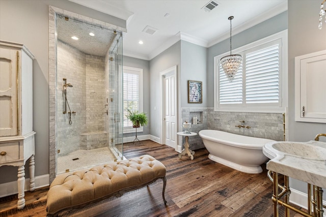 bathroom featuring a shower stall, crown molding, a freestanding bath, wood finished floors, and a chandelier