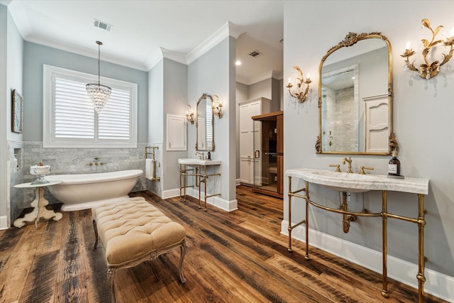 full bathroom featuring a soaking tub, crown molding, a wainscoted wall, and wood finished floors