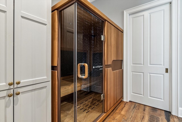 bathroom with wood finished floors and a shower stall