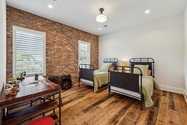 bedroom featuring hardwood / wood-style floors, brick wall, baseboards, and recessed lighting
