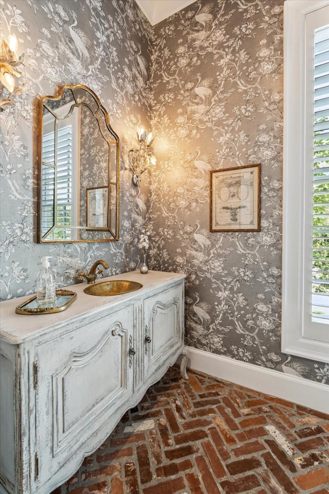 bathroom featuring baseboards, vanity, and brick flooring