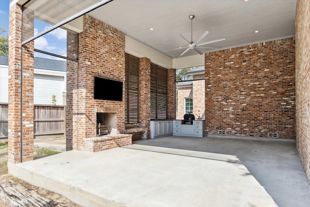 view of patio featuring an outdoor brick fireplace, ceiling fan, fence, and grilling area
