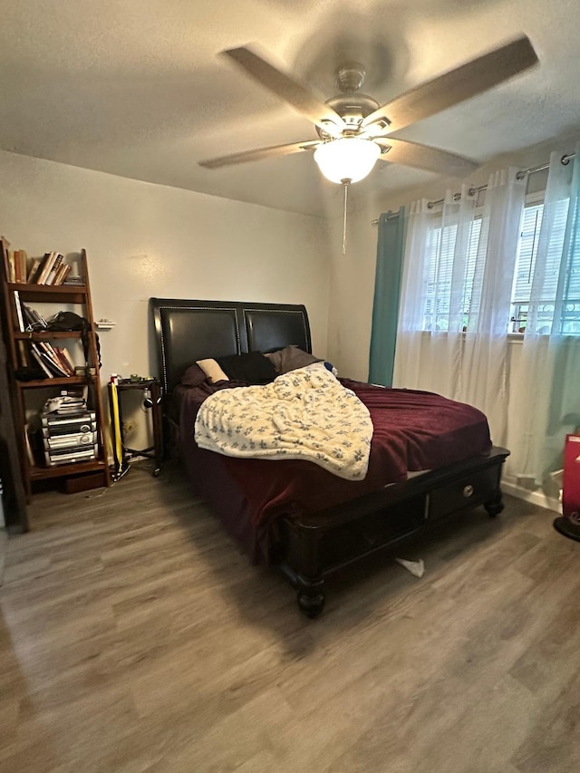 bedroom with ceiling fan, wood finished floors, and a textured ceiling