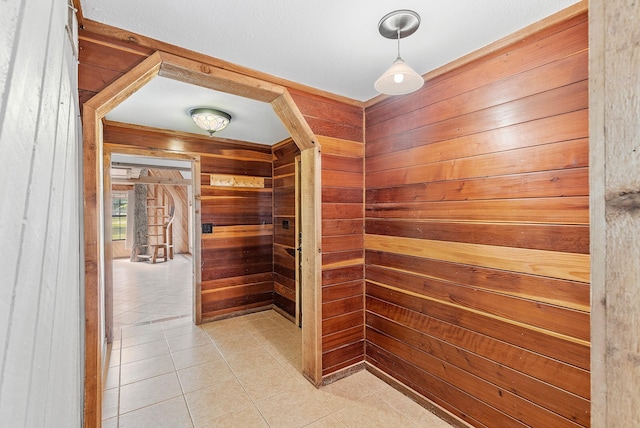 hall featuring wooden walls and light tile patterned flooring