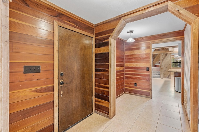 foyer entrance featuring wood walls and light tile patterned floors