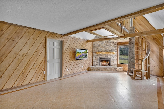 unfurnished living room featuring tile patterned floors, wooden walls, a fireplace, and a textured ceiling