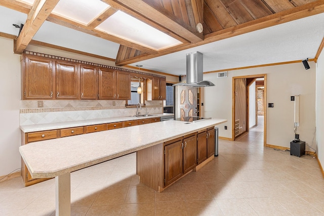 kitchen featuring light countertops, a sink, backsplash, and island range hood