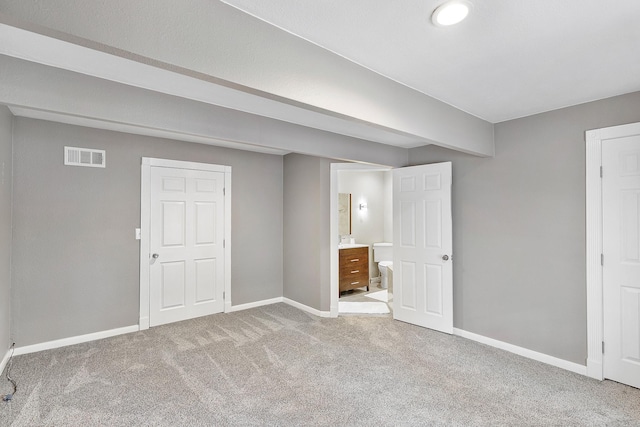 interior space with ensuite bath, carpet, visible vents, and baseboards