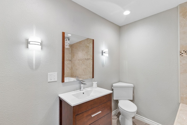bathroom featuring a textured wall, walk in shower, vanity, and toilet