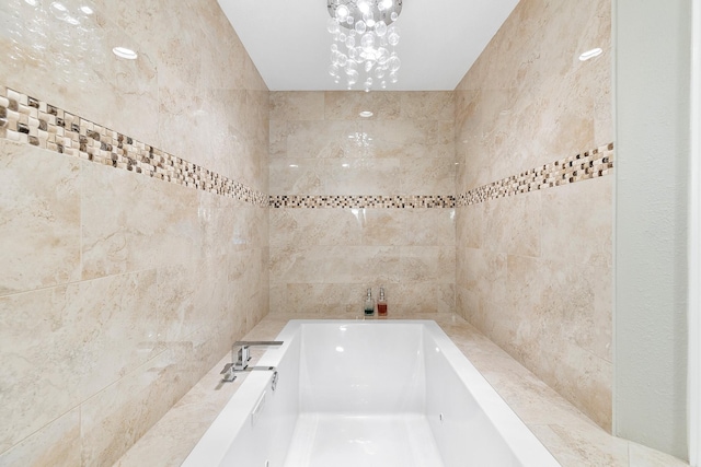 bathroom featuring a garden tub and a notable chandelier
