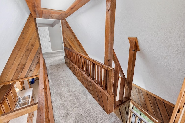 staircase with a textured wall and carpet flooring