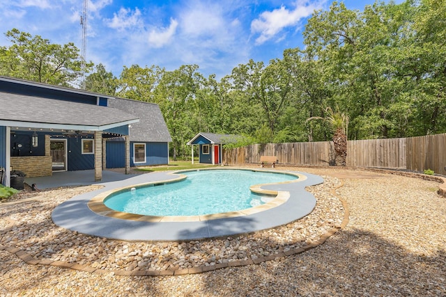 view of swimming pool featuring a patio area, a fenced backyard, a fenced in pool, and an outbuilding