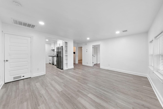 unfurnished living room with baseboards, light wood-style flooring, visible vents, and recessed lighting