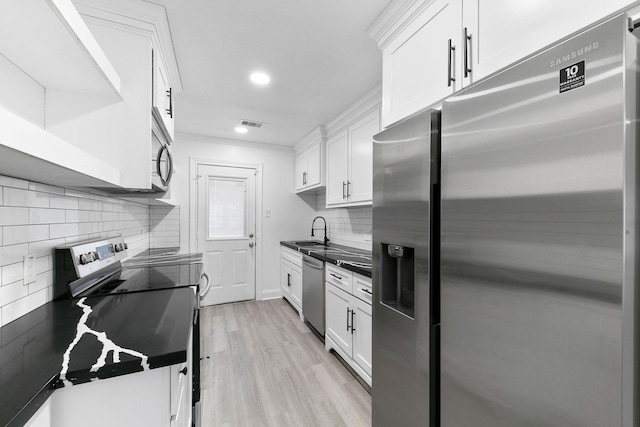 kitchen featuring white cabinets, stainless steel appliances, a sink, and dark countertops