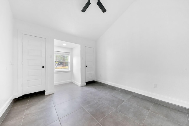 spare room featuring tile patterned flooring, vaulted ceiling, a ceiling fan, and baseboards