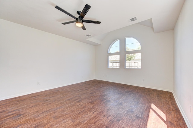 spare room with dark wood-type flooring, lofted ceiling, visible vents, and a ceiling fan