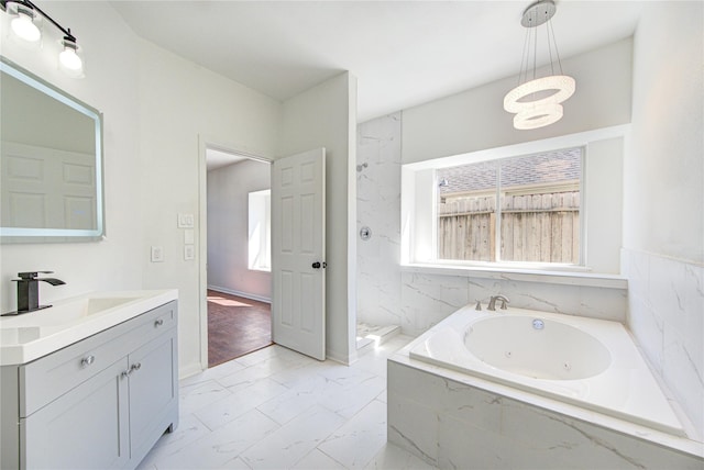 full bathroom with marble finish floor, a healthy amount of sunlight, vanity, and a tub with jets