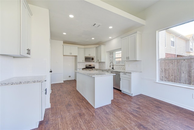 kitchen with tasteful backsplash, a sink, stainless steel appliances, white cabinetry, and visible vents