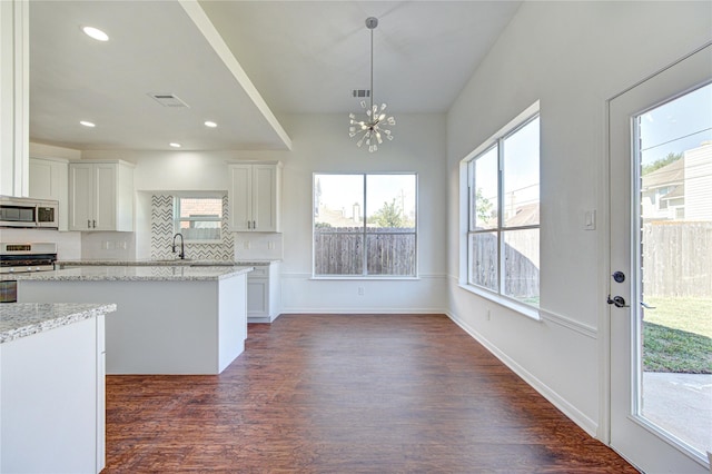 kitchen with a notable chandelier, a sink, stainless steel appliances, white cabinetry, and dark wood-type flooring
