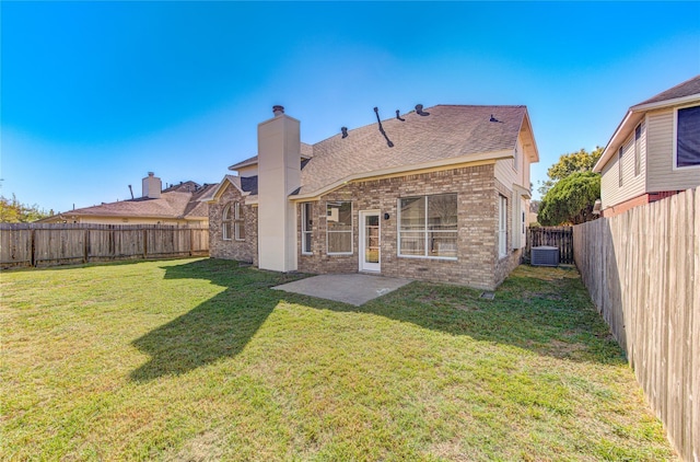 rear view of property featuring a lawn, a chimney, a fenced backyard, cooling unit, and brick siding
