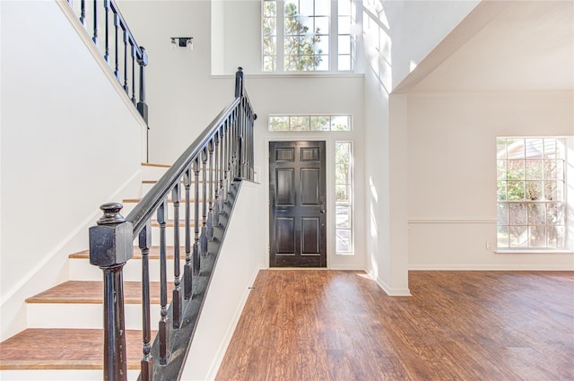 foyer featuring stairs, wood finished floors, a high ceiling, and baseboards