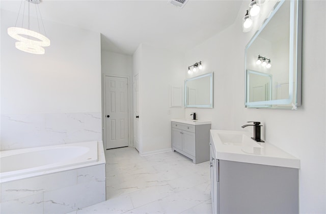 bathroom featuring a garden tub, a sink, marble finish floor, an inviting chandelier, and two vanities