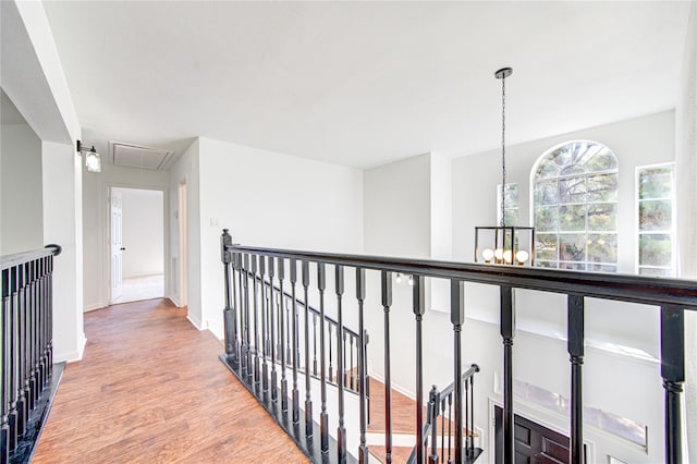 hall featuring wood finished floors, an upstairs landing, attic access, a chandelier, and baseboards