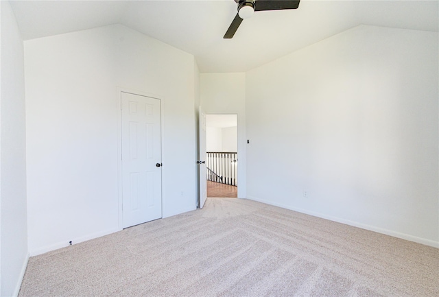 unfurnished bedroom with light carpet, vaulted ceiling, baseboards, and ceiling fan