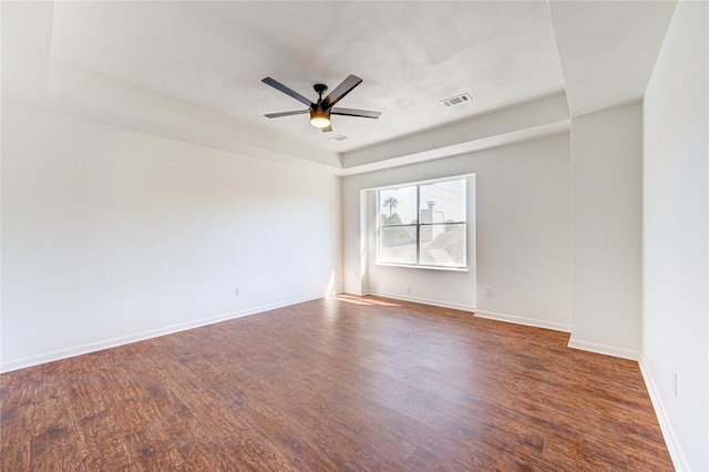 spare room with dark wood-style floors, baseboards, a ceiling fan, and visible vents