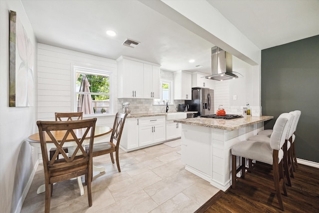 kitchen with stainless steel appliances, extractor fan, visible vents, a sink, and tasteful backsplash