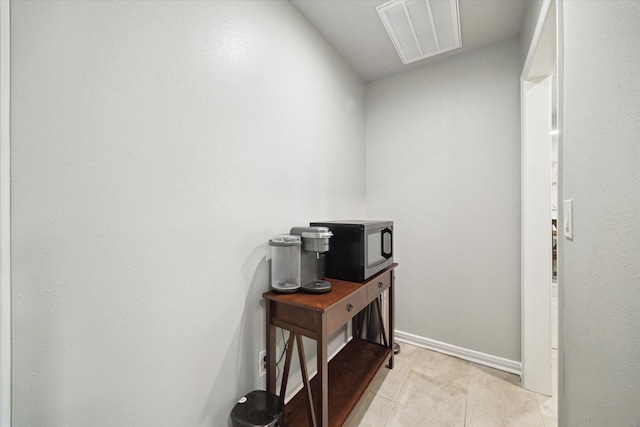 hallway featuring visible vents, baseboards, and light tile patterned floors