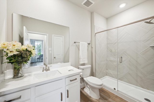 full bath featuring toilet, visible vents, wood finished floors, a shower stall, and vanity