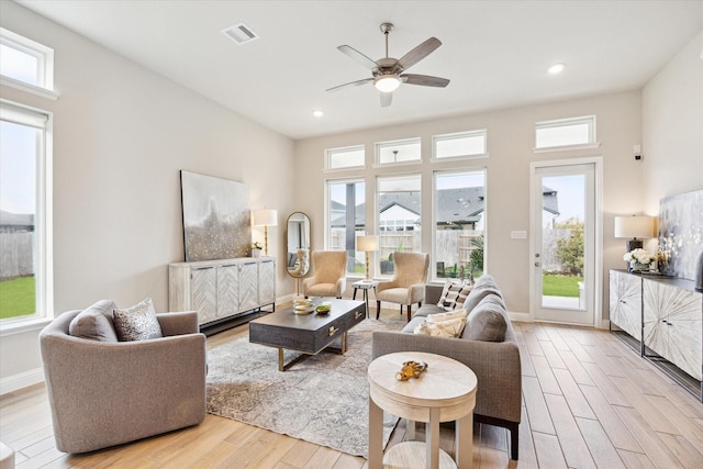 living area with visible vents, wood finished floors, a wealth of natural light, and ceiling fan