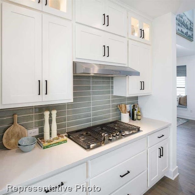 kitchen featuring under cabinet range hood, tasteful backsplash, stainless steel gas stovetop, and light countertops