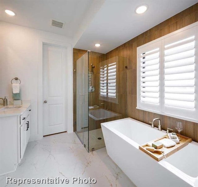full bath featuring marble finish floor, recessed lighting, a freestanding bath, and a stall shower